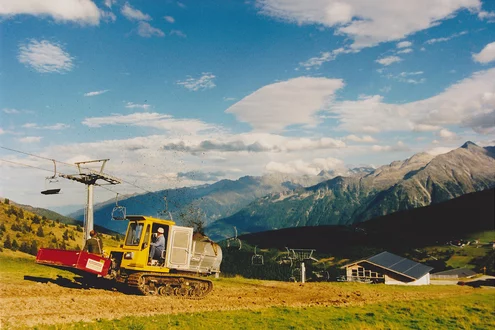 Pistenraupe mit Stöckl Aufbauseitenstreuer bei der Arbeit auf einer Piste außerhalb der Schisaison